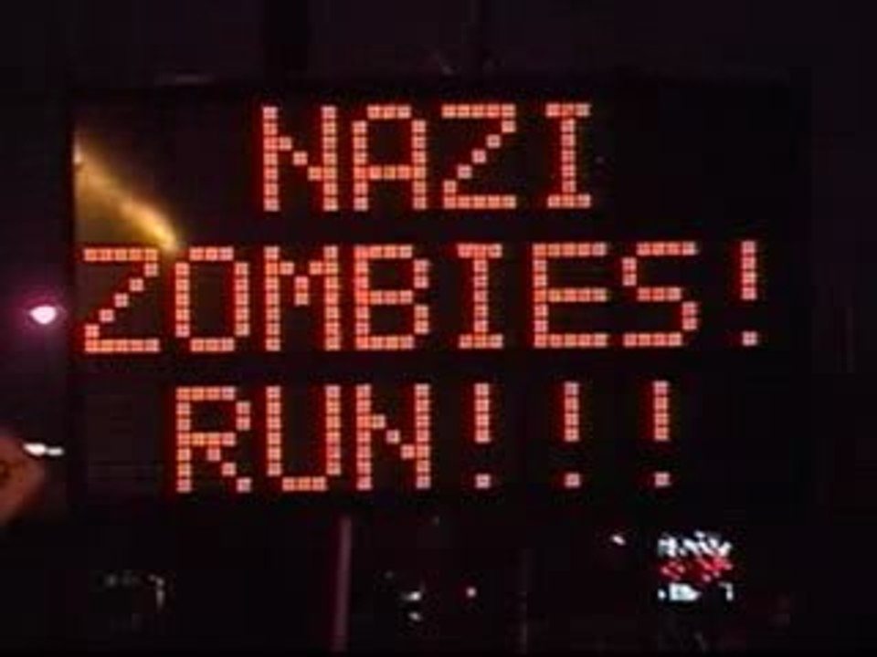 Un panneau d'affichage indique 'Attention zombis !'