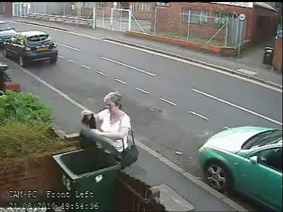 Une femme jette un chat à la poubelle