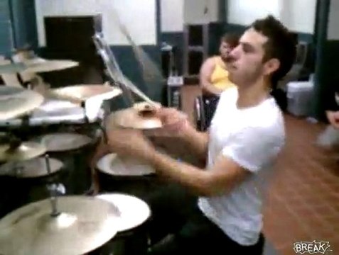 Drummer drums while juggling three drumsticks