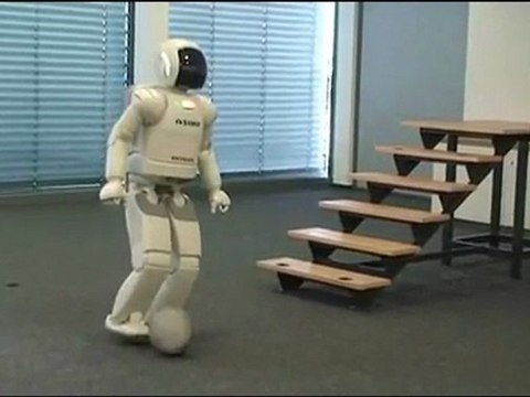 Робот ASIMO играет в футбол