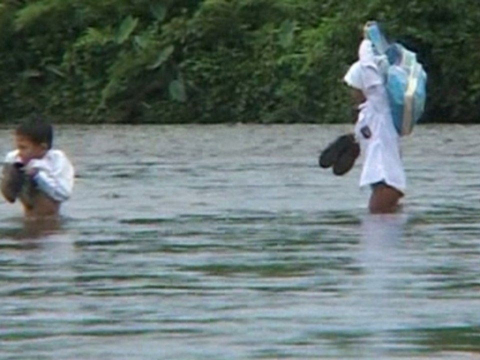 Children walk through a river to get to school