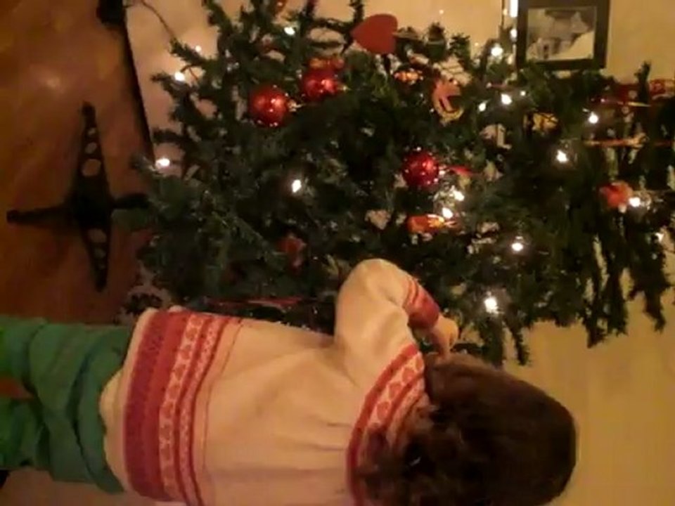 Léonie 2 ans, décore le sapin de Noël.