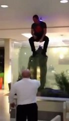 Regardez cet homme sauter dans l'aquarium rempli de poissons d'un hôtel