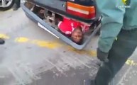 Homme caché dans le pare-choc d'une voiture