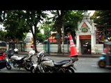 Roadside temple, tuk-tuks and traffic in Bangkok city