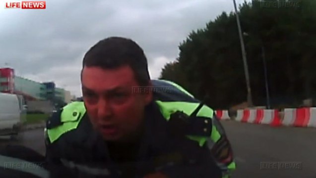 Un policier russe accroché sur un capot de voiture