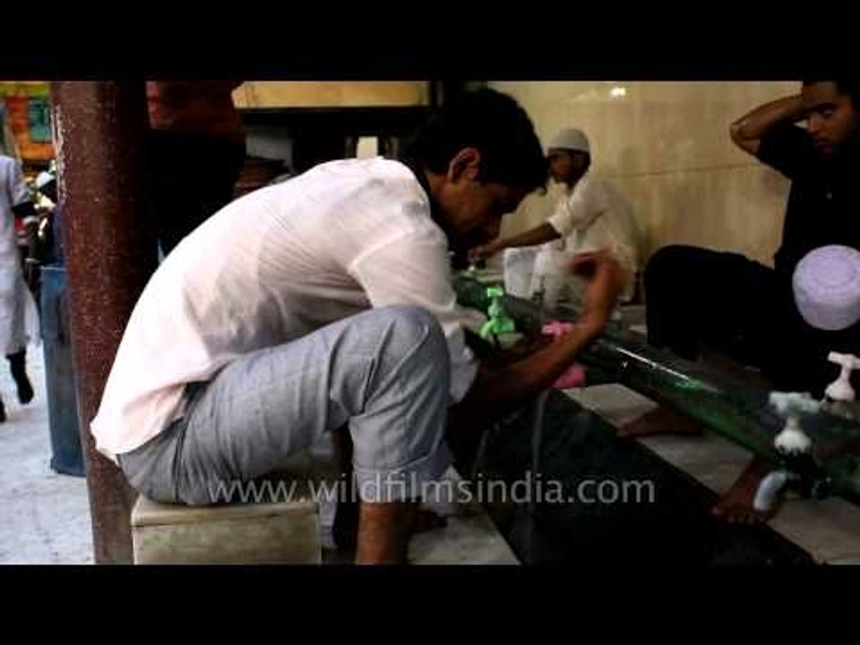 Young Muslim devotee performing wudu before Iftar at Nizamuddin Dargah