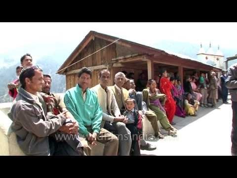People wait below snow-covered peaks, for the Gangotri idol to migrate down