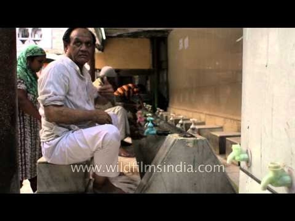Muslim man performing ablution before standing in prayer inest - Nizamuddin Dargah