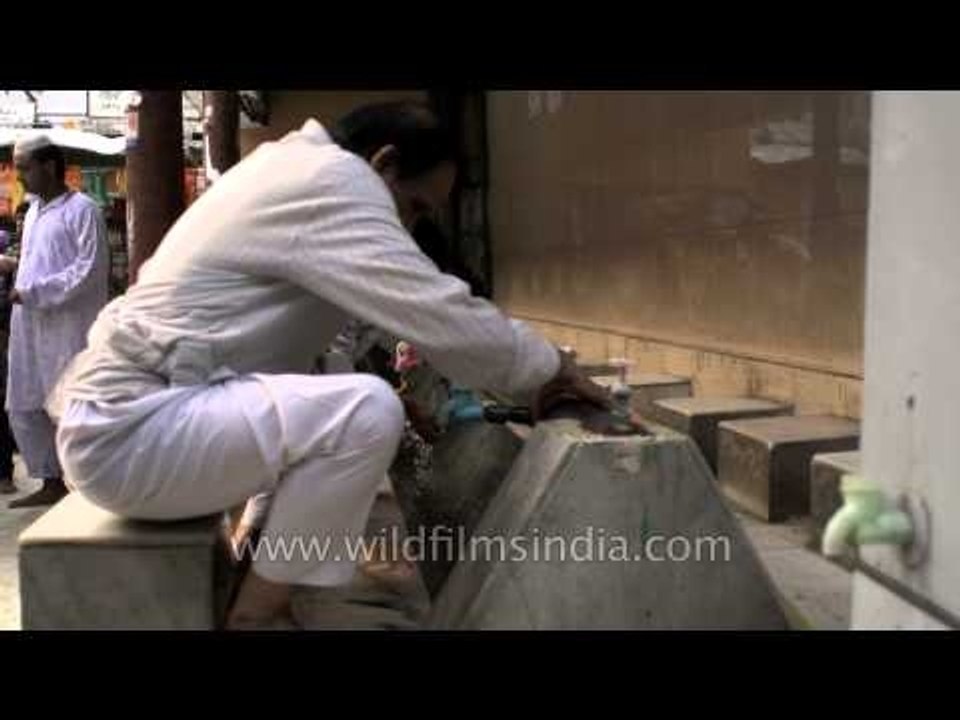 Muslim man performing wuzu before standing in prayer inest - Nizamuddin Dargah
