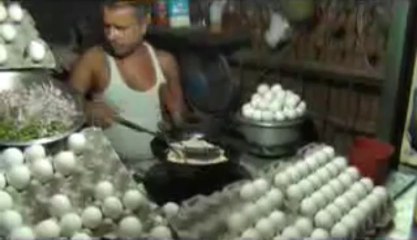 Man cooking Egg Omelette and giving it to customer on bread