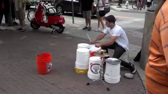 Un excellent batteur de rue joue avec des seaux