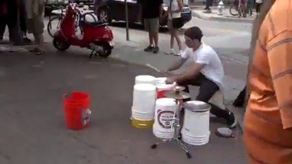 Un excellent batteur de rue joue avec des seaux