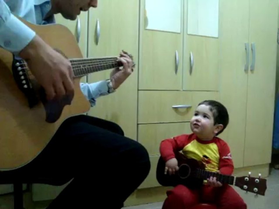 Un enfant joue de la guitare avec son papa