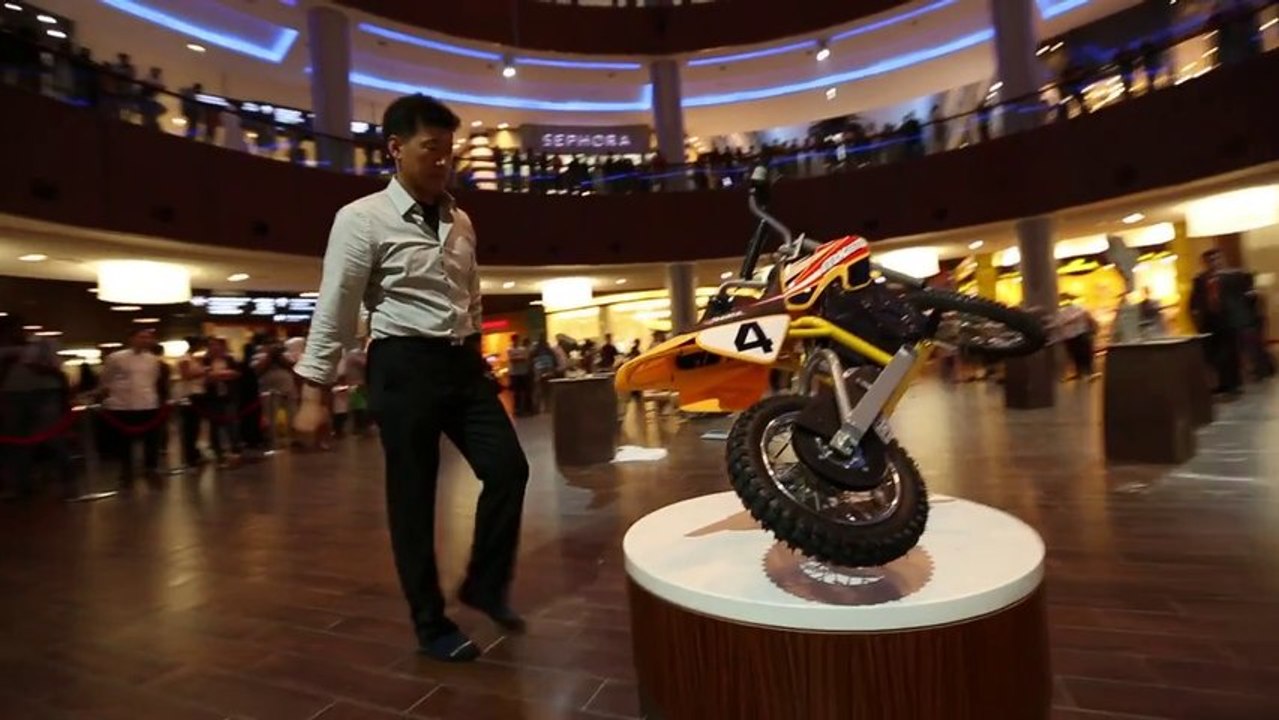 Un artiste met des objets en équilibre dans un centre commercial