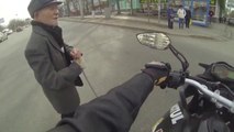 Un motard aide un vieil homme à traverser la route