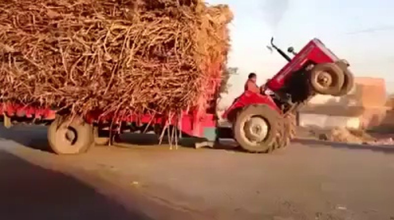 Loaded tractor doing a wheelie on busy road