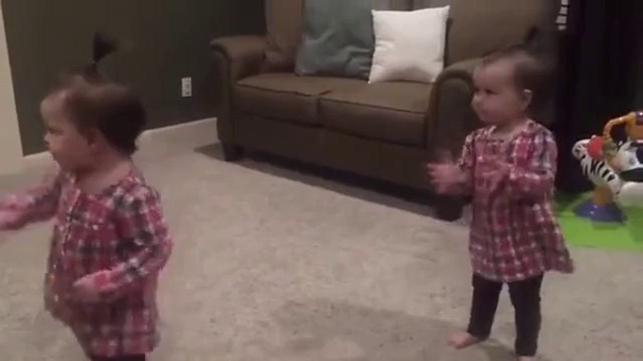 twins baby girls are dancing in their room.