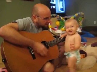 Little Baby Girl Is Singing And Playing Gittar With His Father