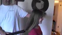 Dad puts daughters hair in a pony tail using a vacuum