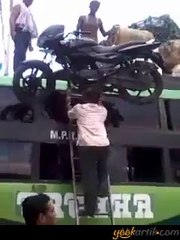 Kafasının üstünde motorsiklet taşıyan adam.