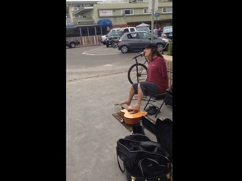 Street performer plays guitar with his feet