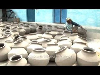 Indian potter woman and her freshly-baked clay pots to store water