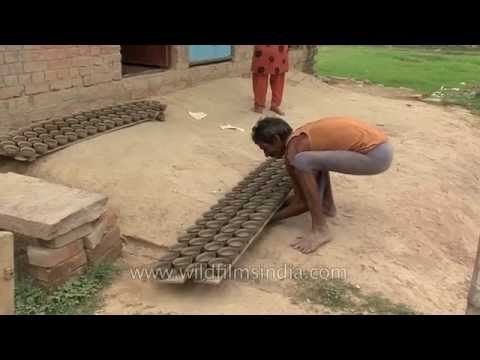 Indian potter dries pottery products outside his house