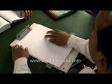 Visually challenged man writing in braille script at Central braille press