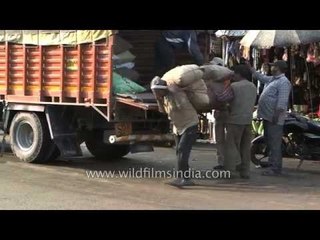 Workers unloading goods from a loaded truck in Lohaghat