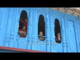 Women peep out of wooden windows, during Kumaoni wedding