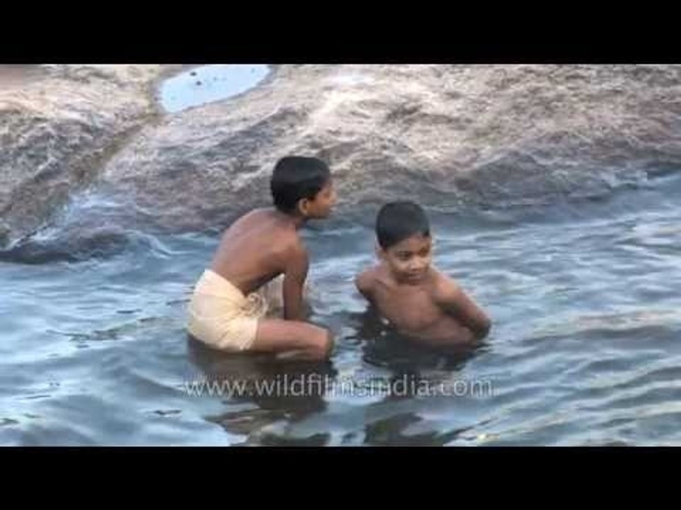 Boys dip into the waters of the river at Thiruvalluvar Temple