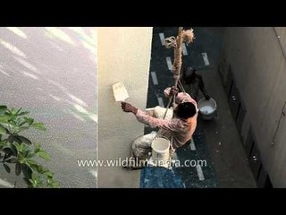 Dangerous job - dangling on a makeshift swing to paint a building!