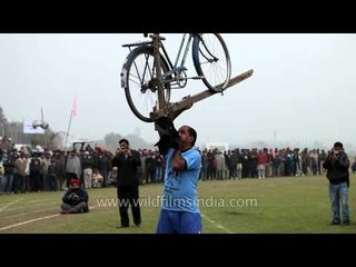 Man balances a plough and a bicycle on his teeth