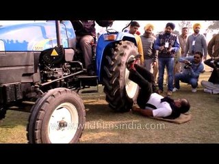 Strange and unusual: Man lies under tractor to test his strength