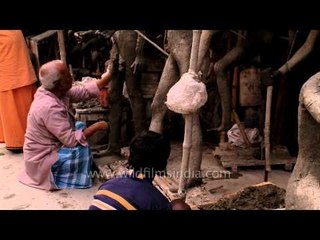 Artisan creates clay legs of human idol