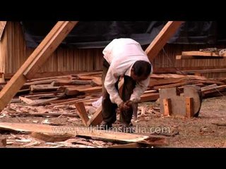 Man carving wood using an axe, in India