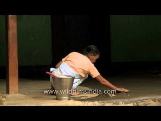 Woman swabbing verendah of house in Manipur