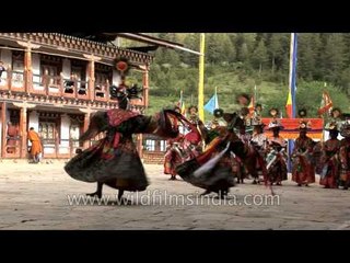 Monks wearing large black hats performs the Shana Cham dance in Bhutan
