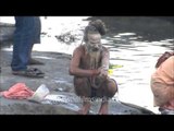 A naga sadhu smears his body with ash after bathing in the River Ganges at Varanasi