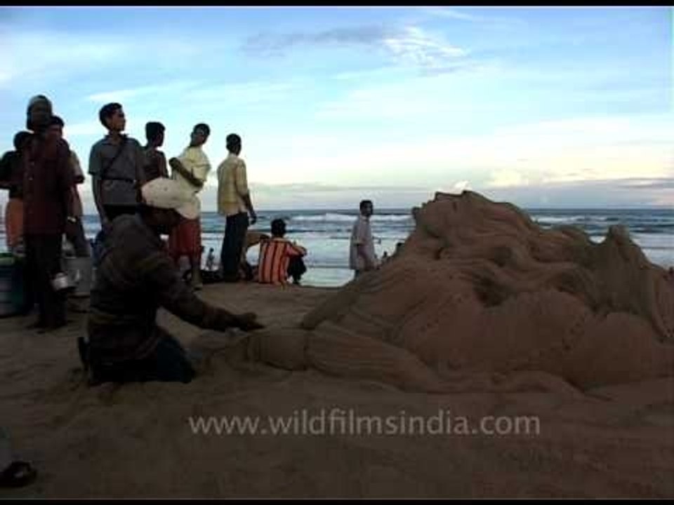 Sand artist sculpting the portrait of a lady by the Bay of Bengal, Puri