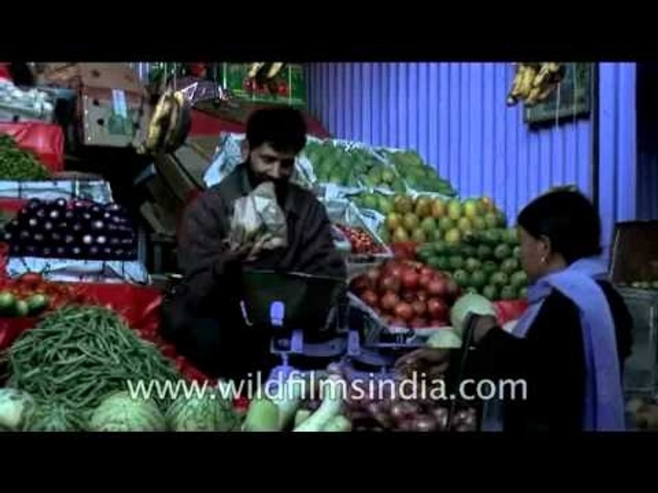 Smiling vendor sells vegetables and fruits in Ladakh.