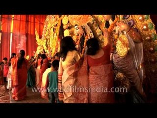 Bengali ladies applying 'Bel Patra' on the huge idle of Goddess Durga