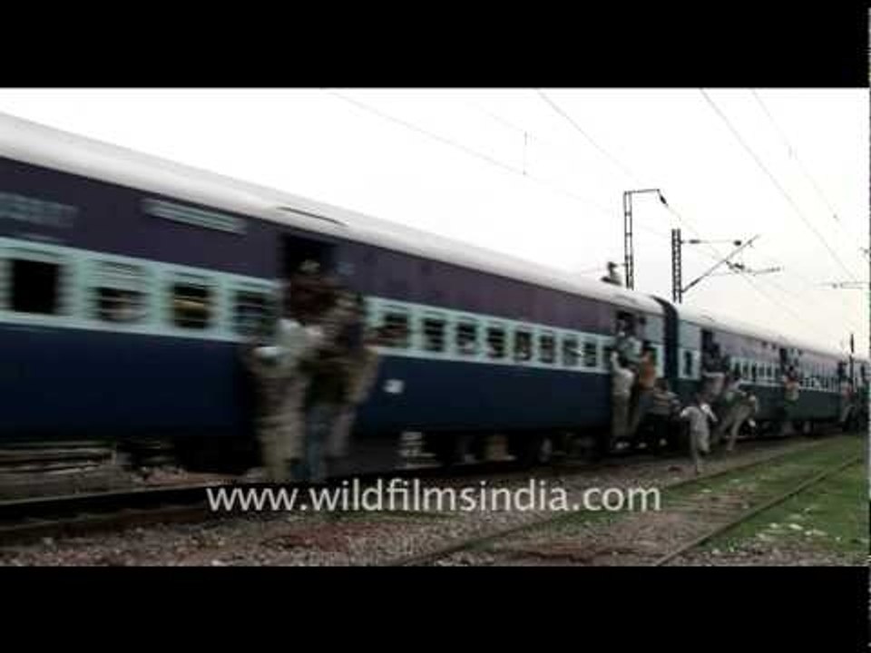 People hanging out of a crowded train in India!