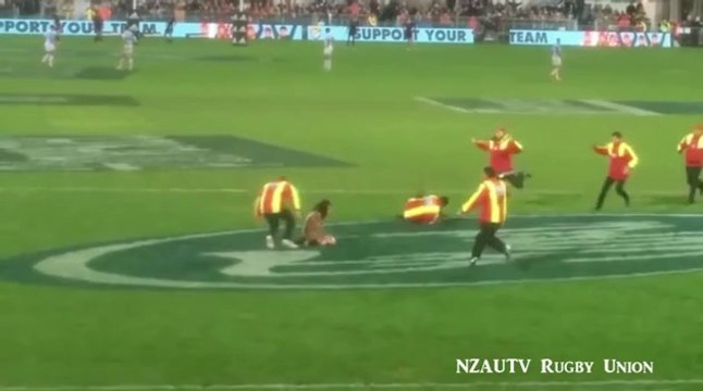 Streaker receives a high tackle from steward at rugby match