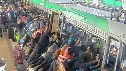 Des passagers poussent un wagon pour aider un homme coincé