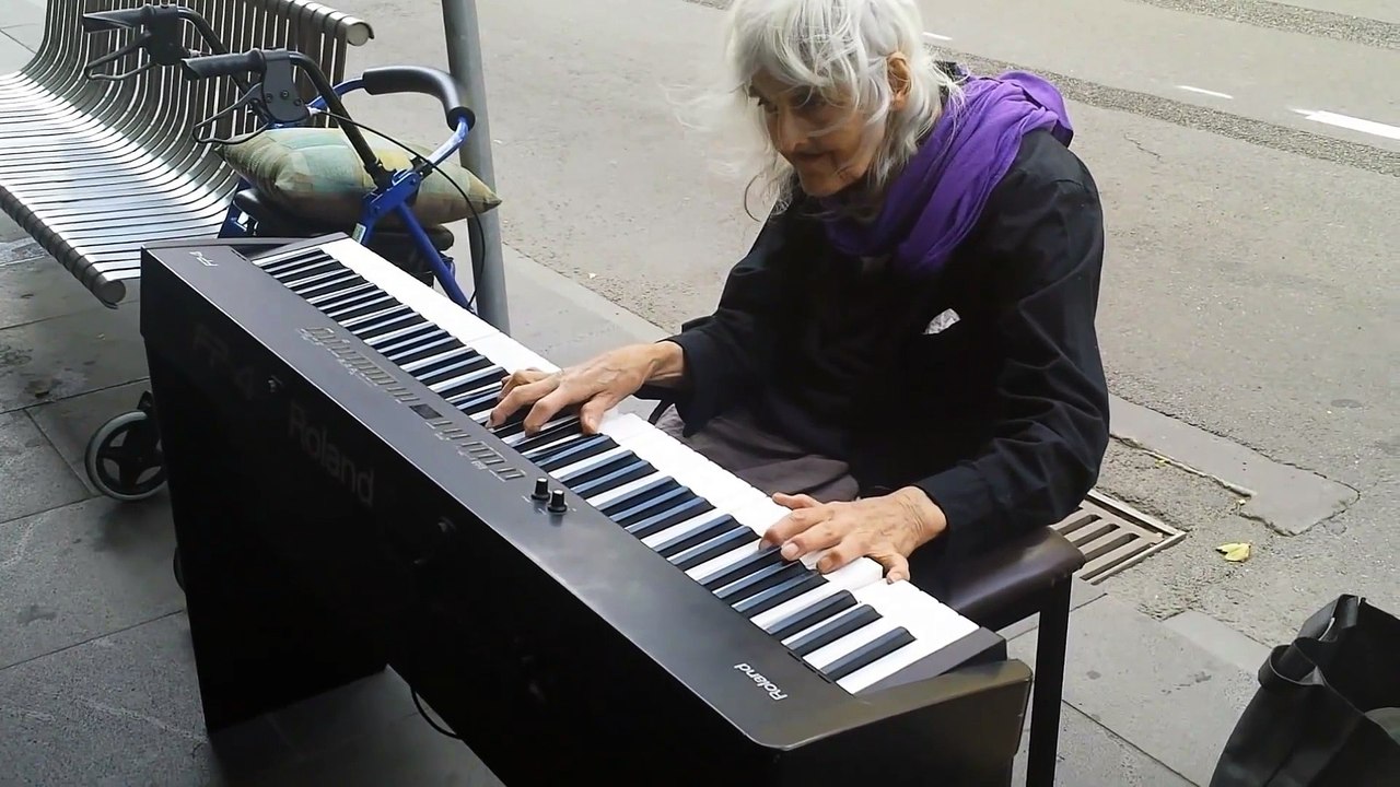 Une vieille dame joue au piano dans la rue pour gagner sa vie
