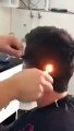 Il utilise un briquet pour coiffer ses clients