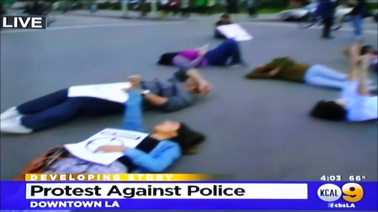 LOS ANGELES ERIC GARNER PROTESTERS LAY DOWN IN STREET. GIRL RAISES COMMUNIST FIST.