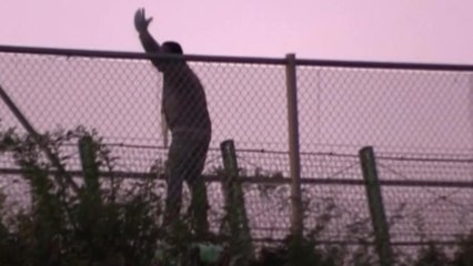 Hundreds of migrants scramble to cross razor wire fence into Spain